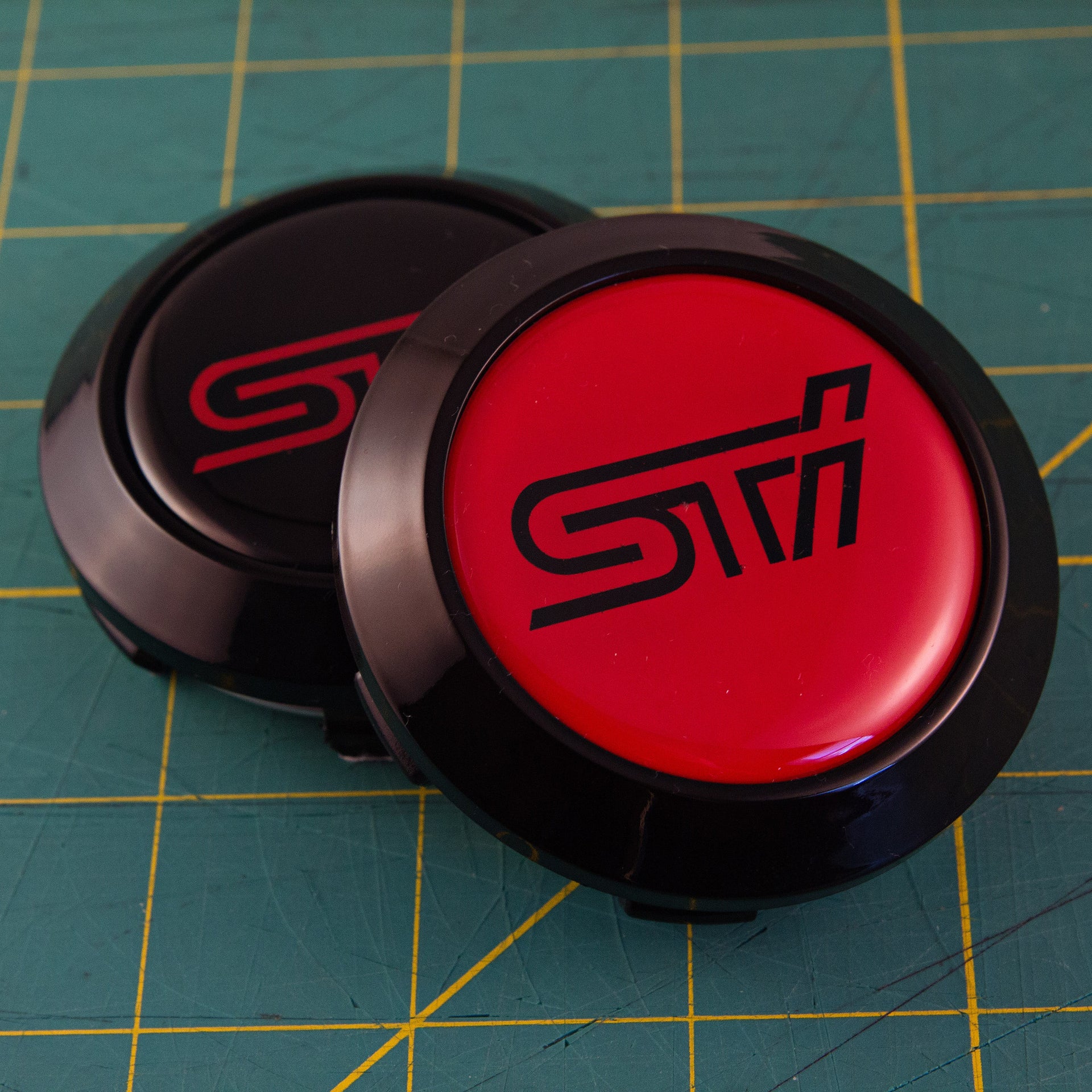 Black STI logo on red background with a black cap